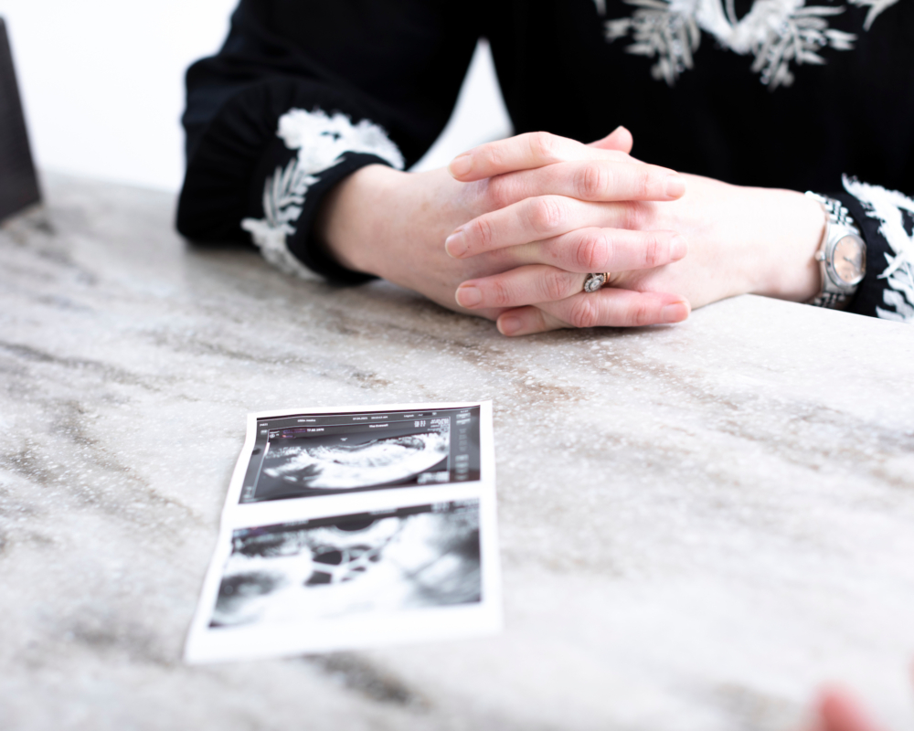 Patient with her ultrasound pictures in front of her on a desk