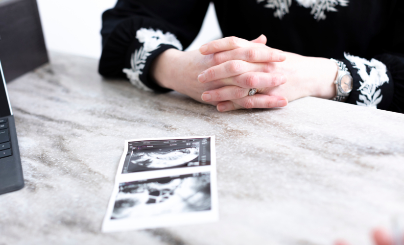 Patient with her ultrasound pictures in front of her on a desk