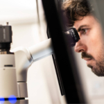 Image of a lab director looking through a microscope doing fertility tests