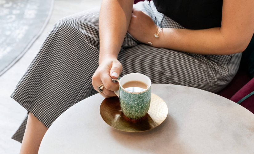 a woman sitting at a chair with a cup of tea discussing she needs help getting pregnant