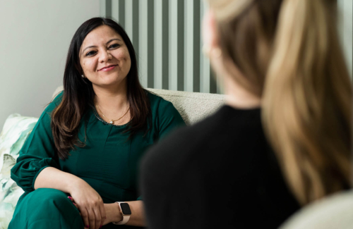 Image of a female consultant sitting on a chair talking to a female patient about PGT-A testing options