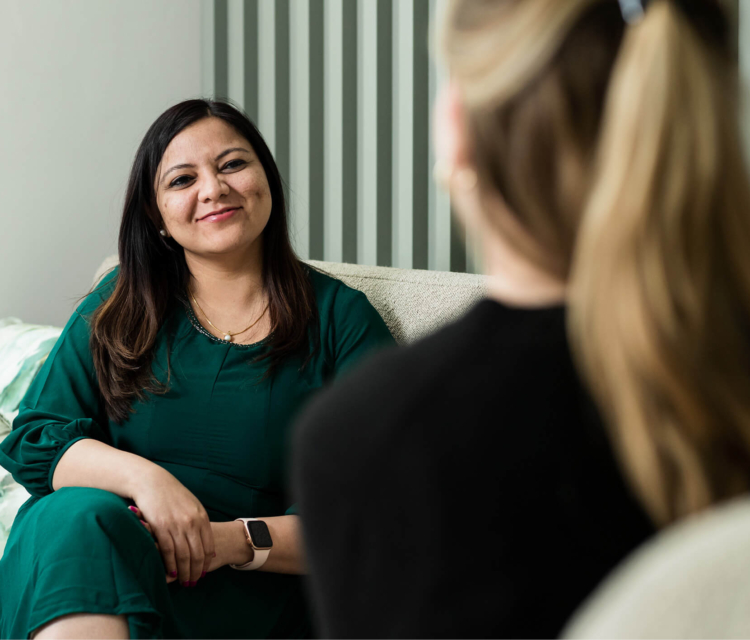 Image of a female consultant sitting on a chair talking to a female patient about PGT-A testing options