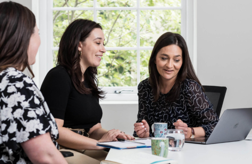 The patient services team at the Evewell sitting at a desk with notes looking at their laptop