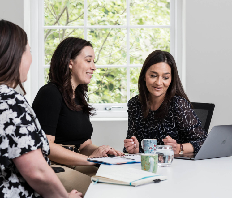 The patient services team at the Evewell sitting at a desk with notes looking at their laptop