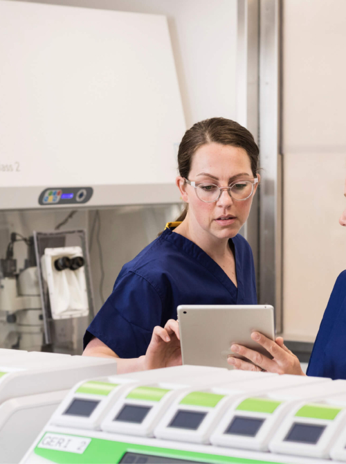 Two embryologists in the laboratory discussing the results of PGT A testing on their ipad